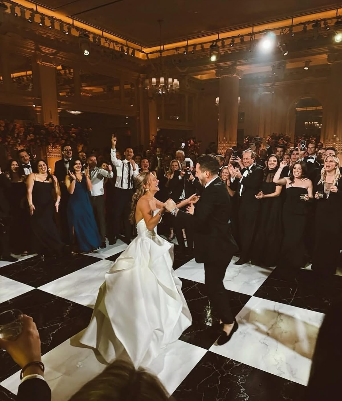 Couple's first dance on a checkerboard patterned dance floor under a tent at a St. Louis reception